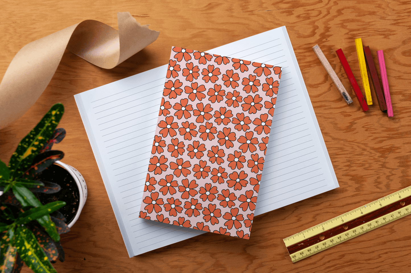 Miss Daisy Classic Layflat Journal Notebook with floral cover on desk surrounded by colorful pens, ruler, and plant, perfect for journaling.