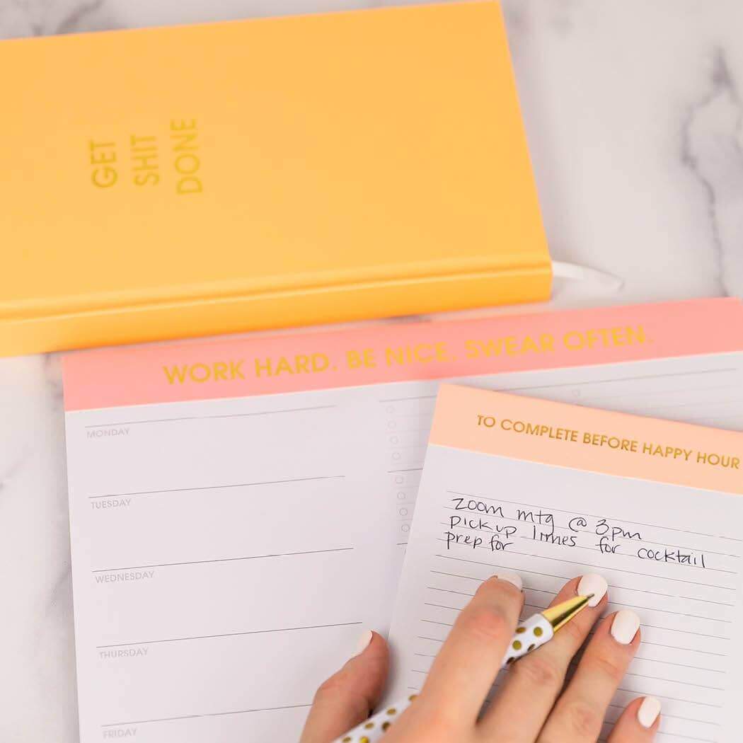 Hand writing in Get S*** Done journal with Mimosa Orange cover and motivational notepad.