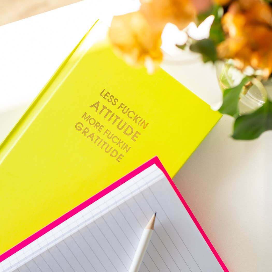 Neon yellow gratitude journal with gold foil text, next to a lined notebook and pencil, perfect for guided journaling and journal prompts.