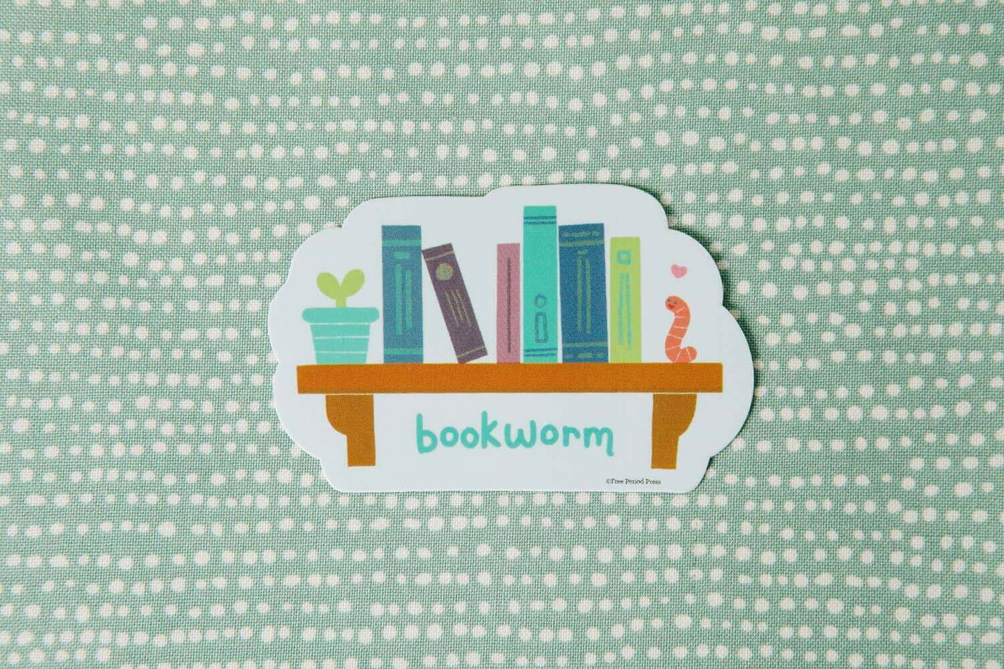 Cute bookworm vinyl decal sticker featuring books and a tiny worm, perfect for journals, laptops, and more.