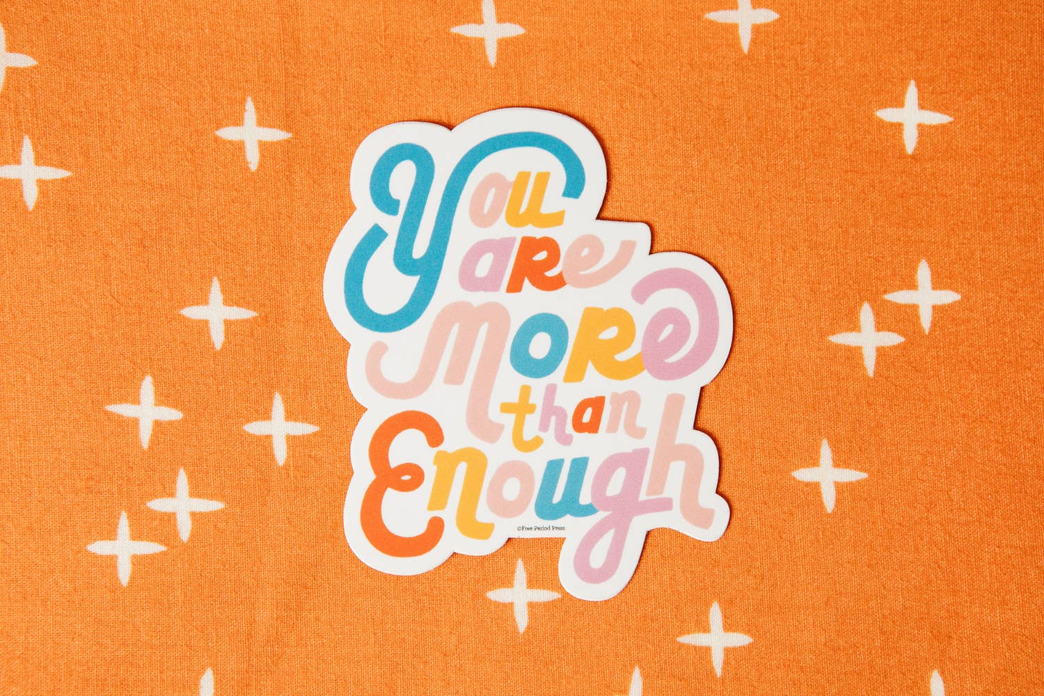 "You Are More Than Enough vibrant vinyl decal sticker on an orange background, perfect for journals, laptops, and water bottles."