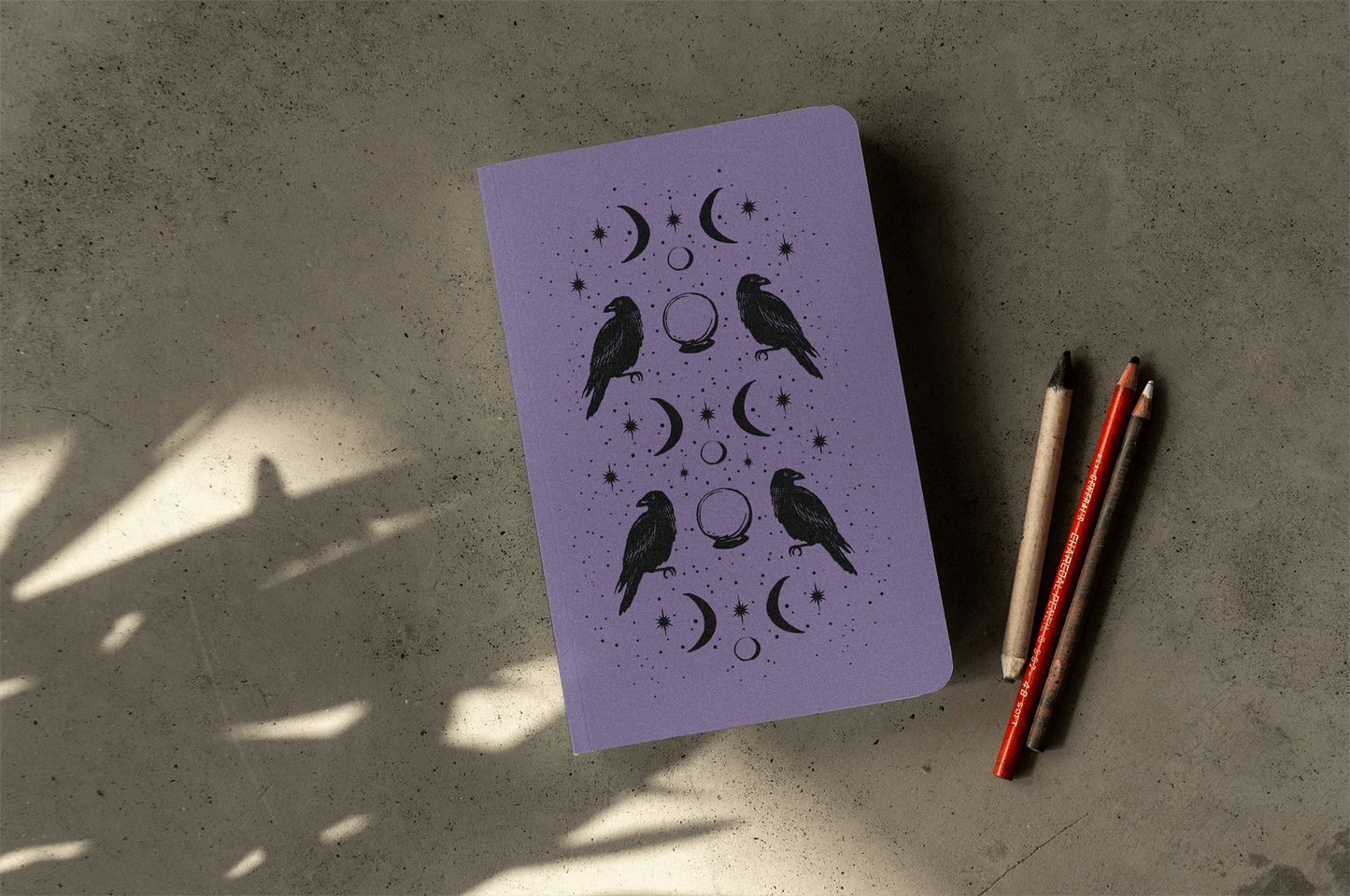 Raven of Fortune Layflat Journal Notebook with cosmic design, perfect for journaling and guided prompts; displayed with pencils.