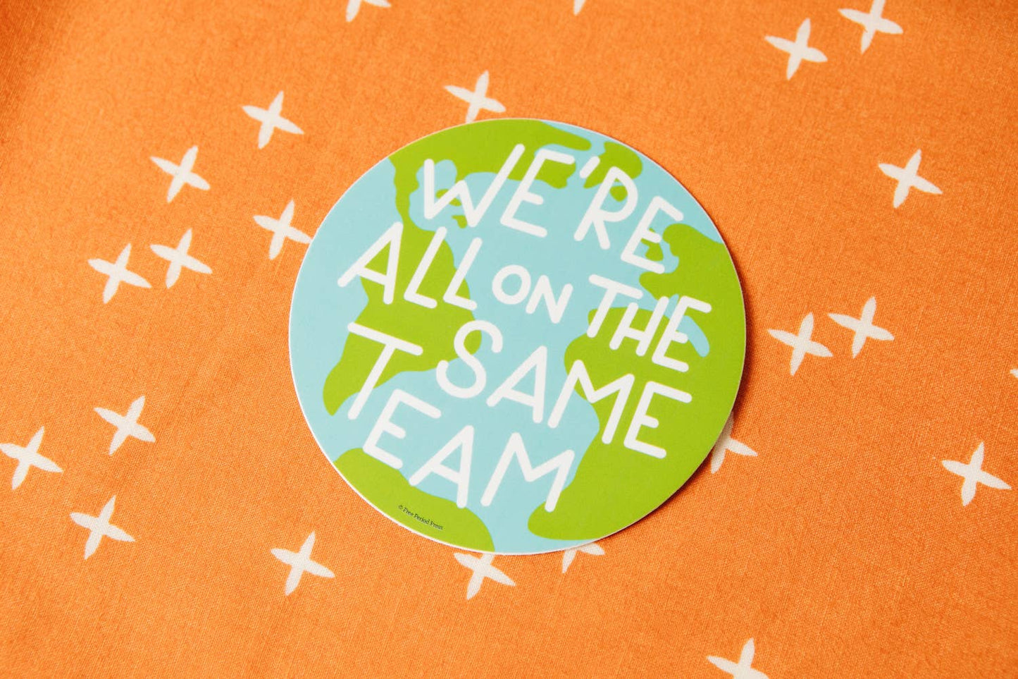 Same Team Earth Vinyl Decal Sticker promoting teamwork and sustainability on an orange background with white crosses.