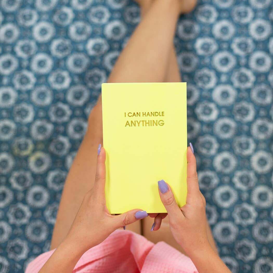 Bright lemon yellow "I Can Handle Anything" journal with gold foil cover held by two hands, perfect for journaling prompts and guided journaling.