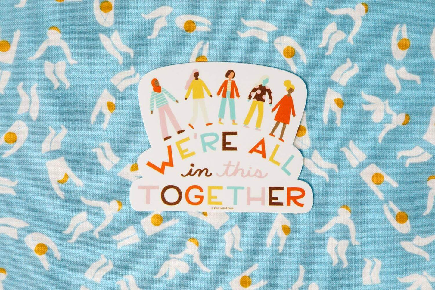 "We're All in This Together" vinyl decal sticker, perfect for laptops and journal supplies, on a colorful patterned background.