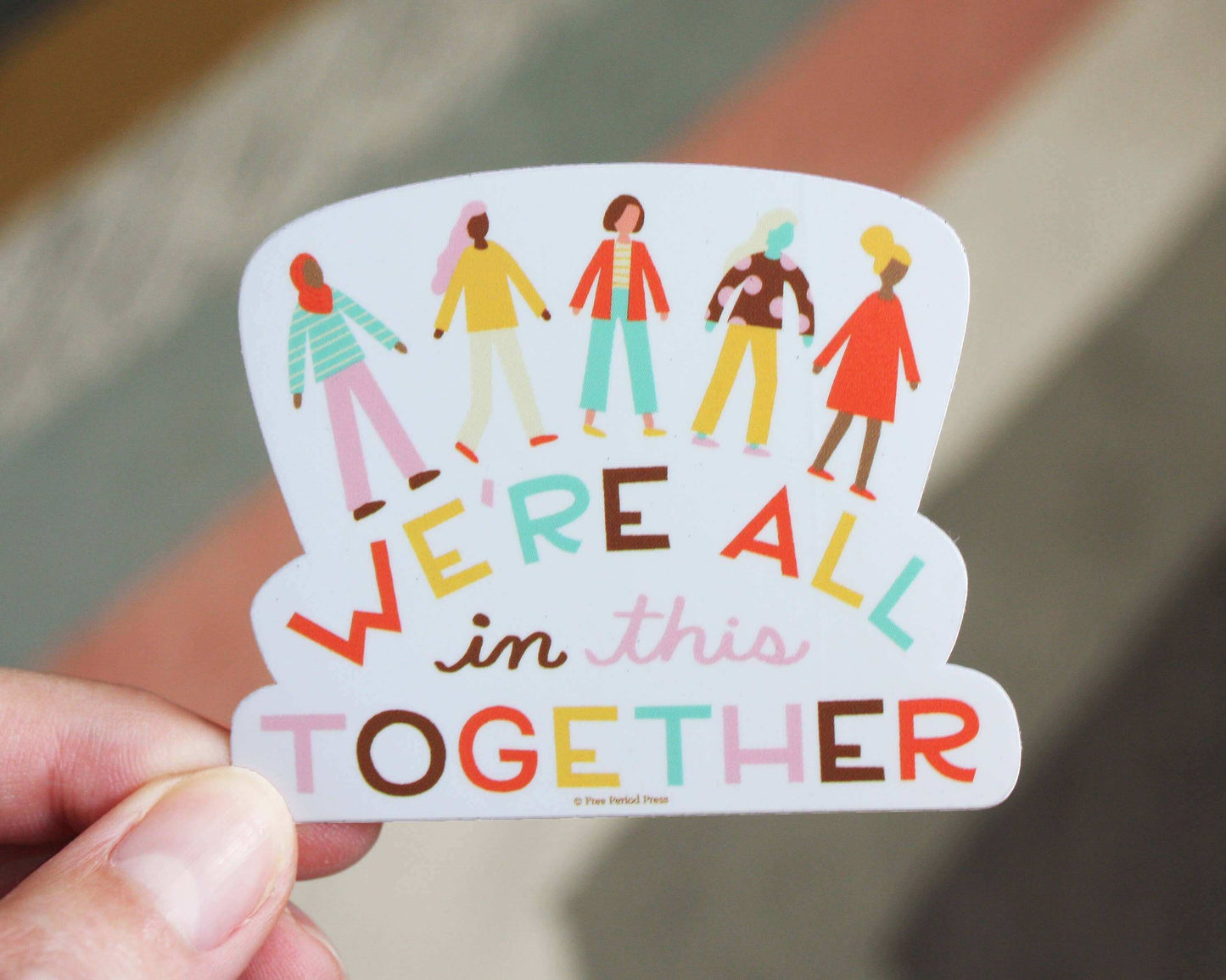 Vibrant "We're All in This Together" vinyl decal sticker for journaling and laptops, hand holding sticker against blurred background