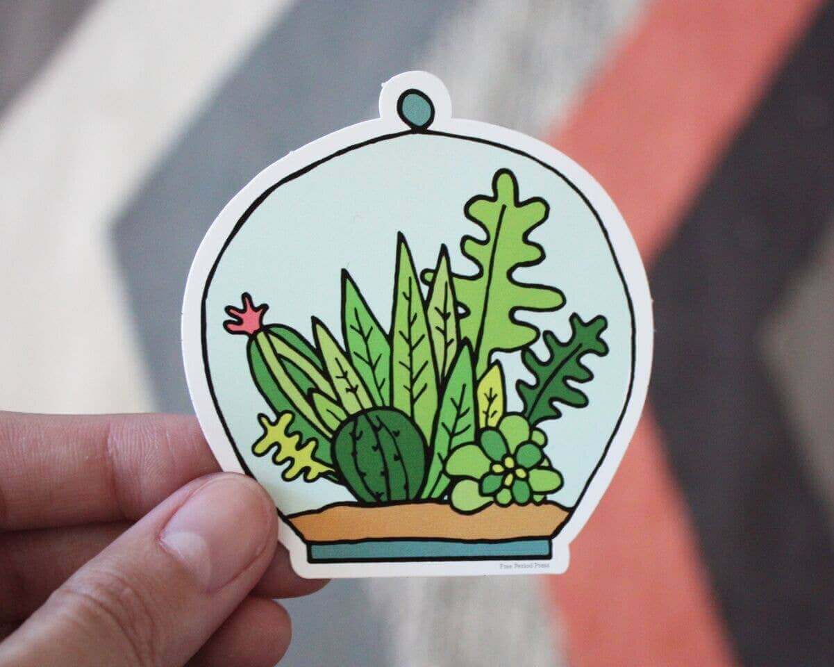 Succulent Terrarium Vinyl Decal Sticker held by hand, perfect for journaling on laptops, water bottles, or phones. Designed by Katie Daugherty.