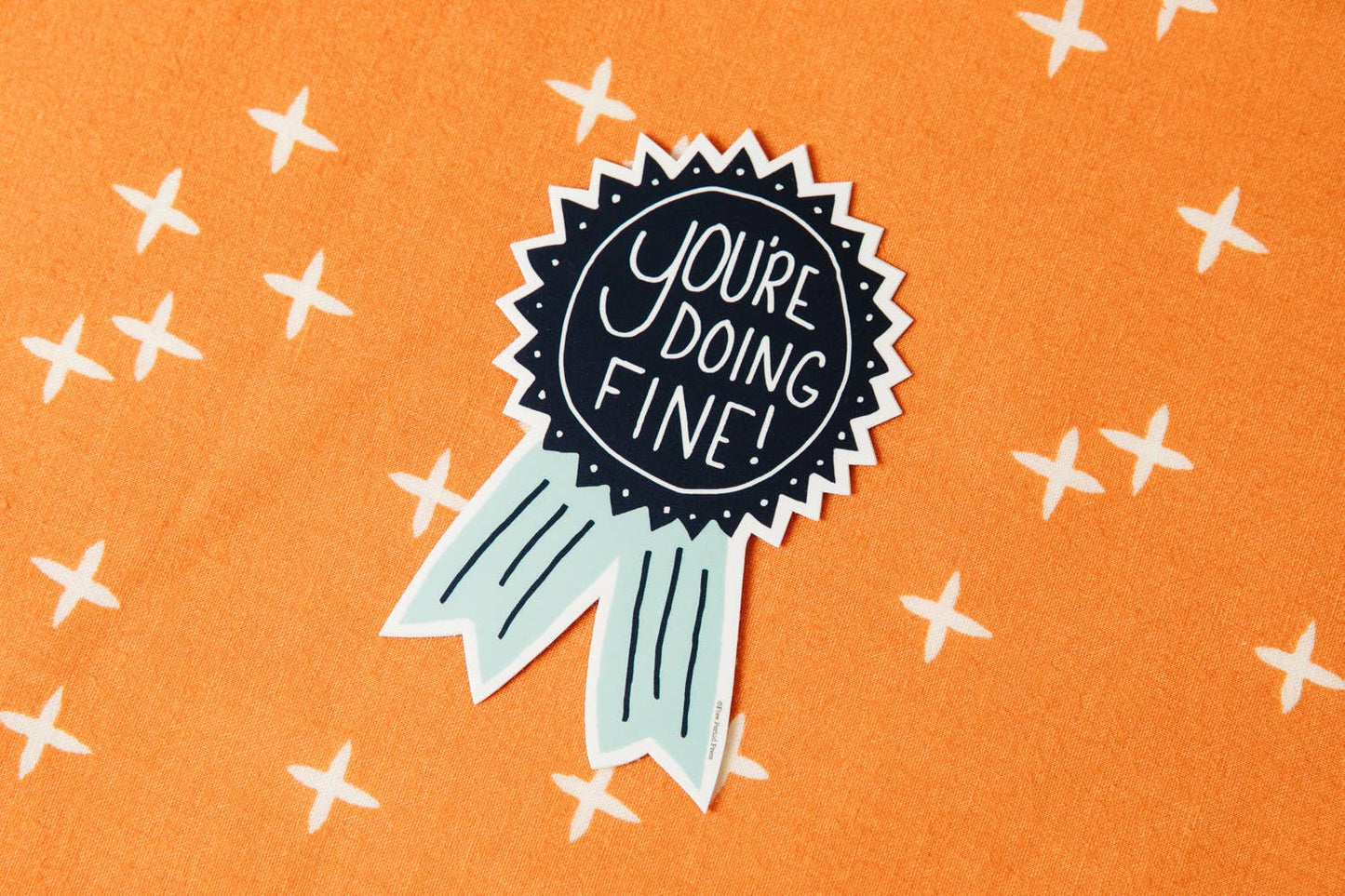 Bright "You're Doing Fine" vinyl decal sticker on an orange patterned background perfect for laptops, journals, and water bottles.