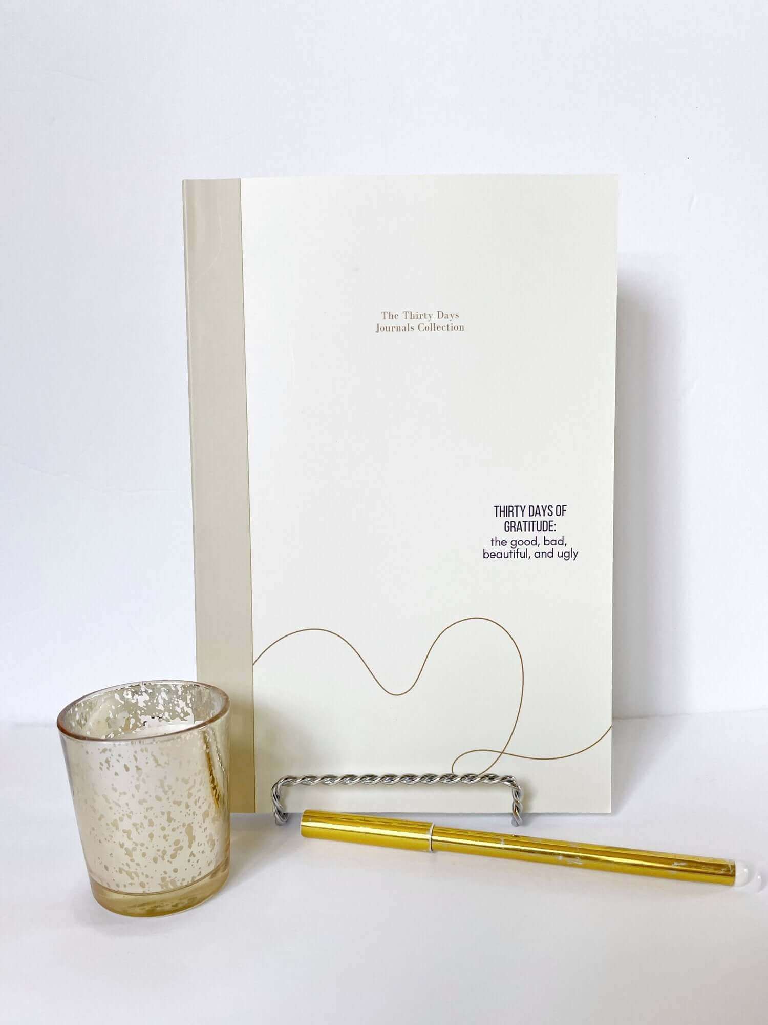 Thirty Days of Gratitude journal, featuring good, bad, beautiful, and ugly prompts, with a golden pen and candle, on a white background.