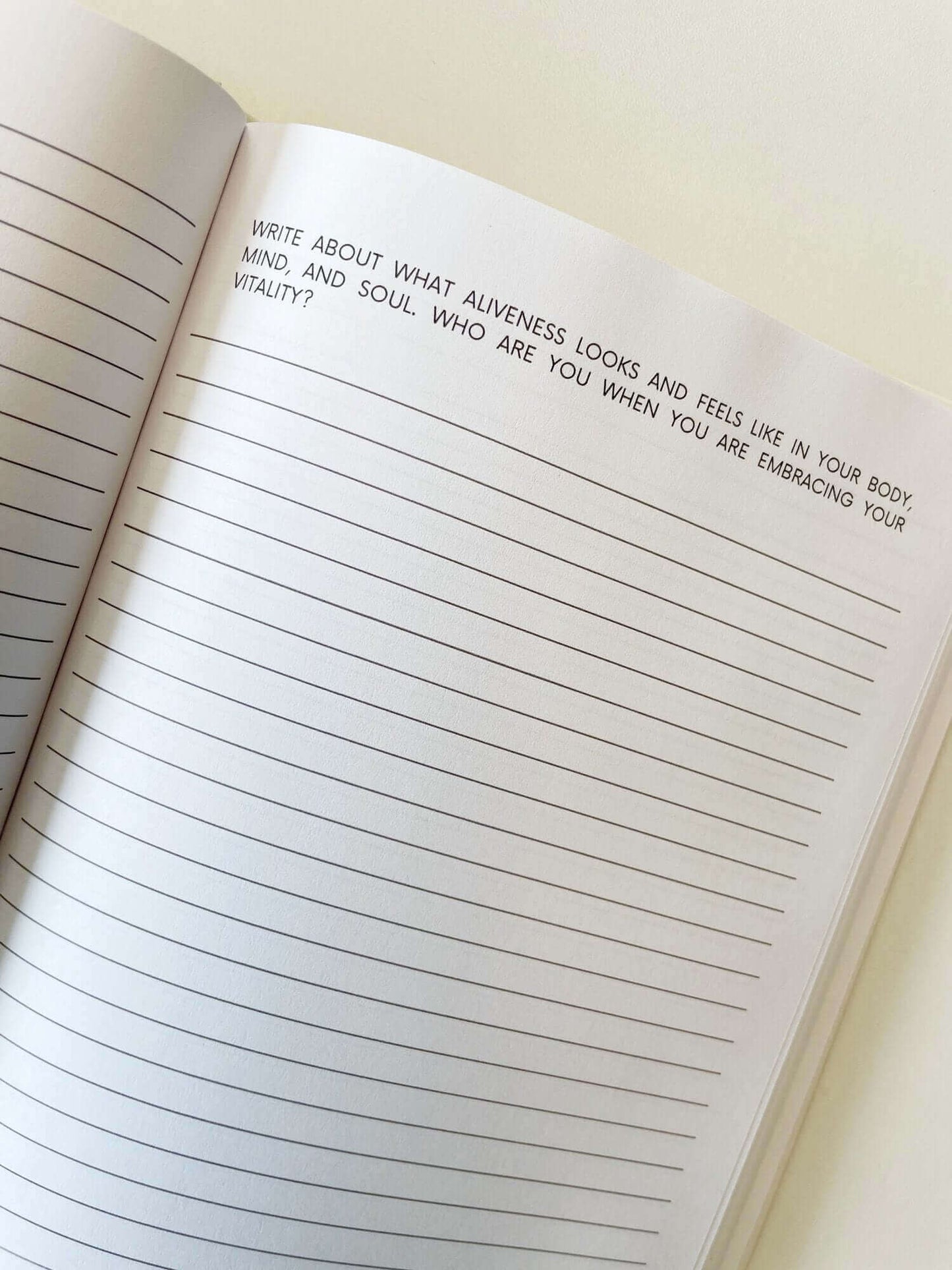 Open journal with thought-provoking prompt about self-discovery and vitality. Blank lined pages ready for journaling journey.