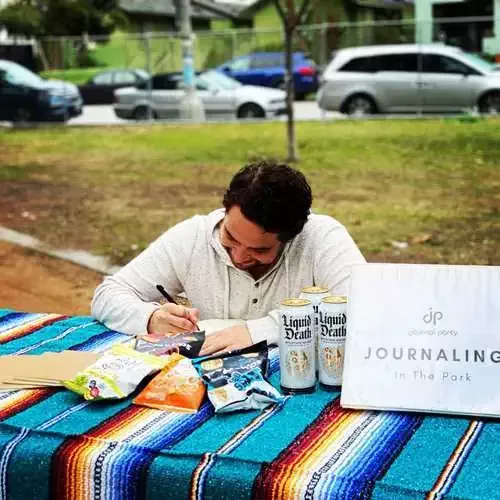 A journaler outdoors in a park, mid-practice.