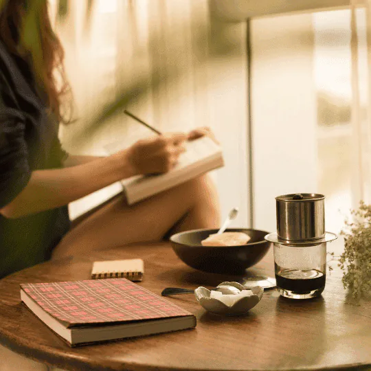A woman sitting down to write the first page of her notebook.
