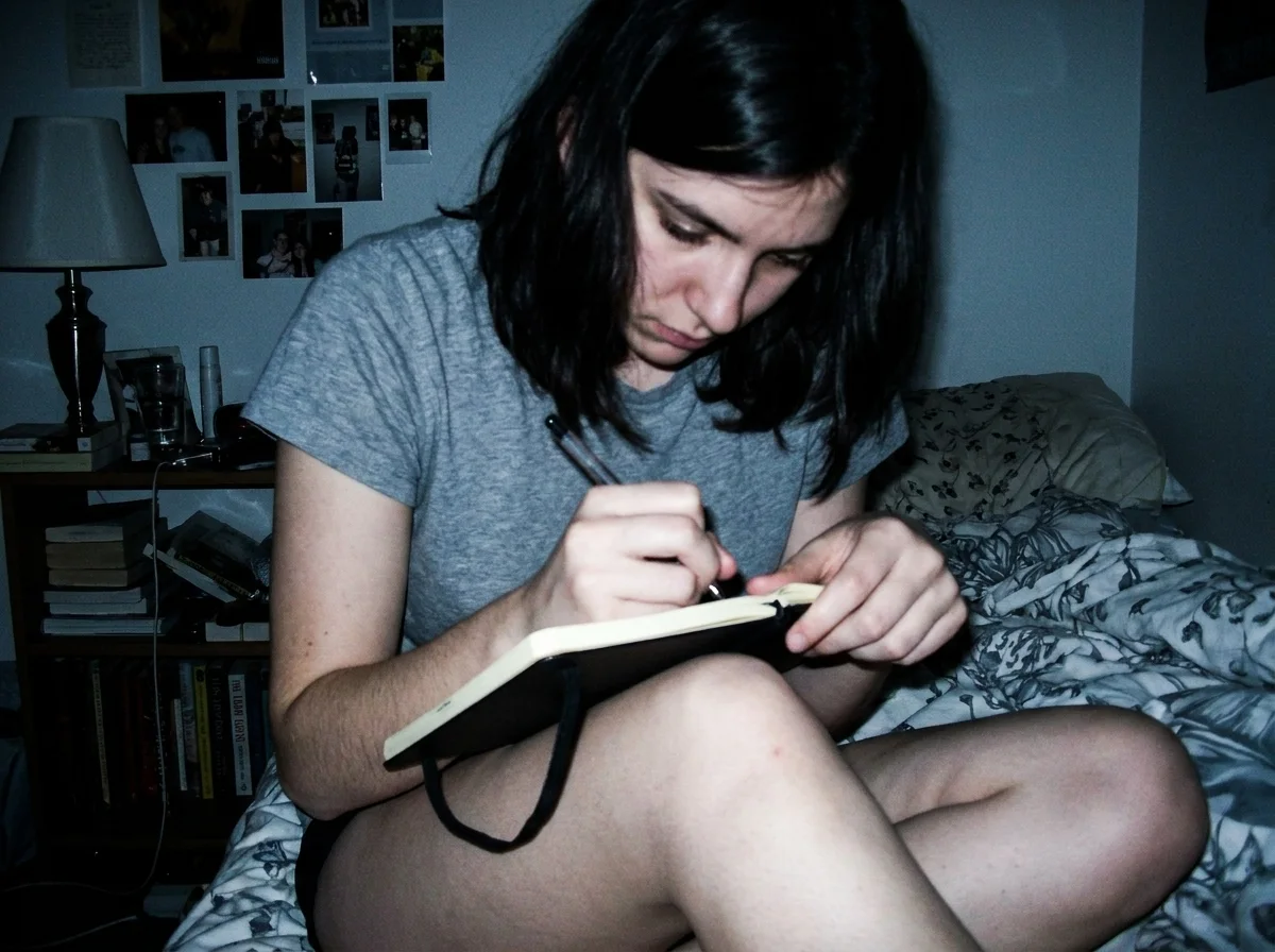 Hands holding a pen over an open paper journal