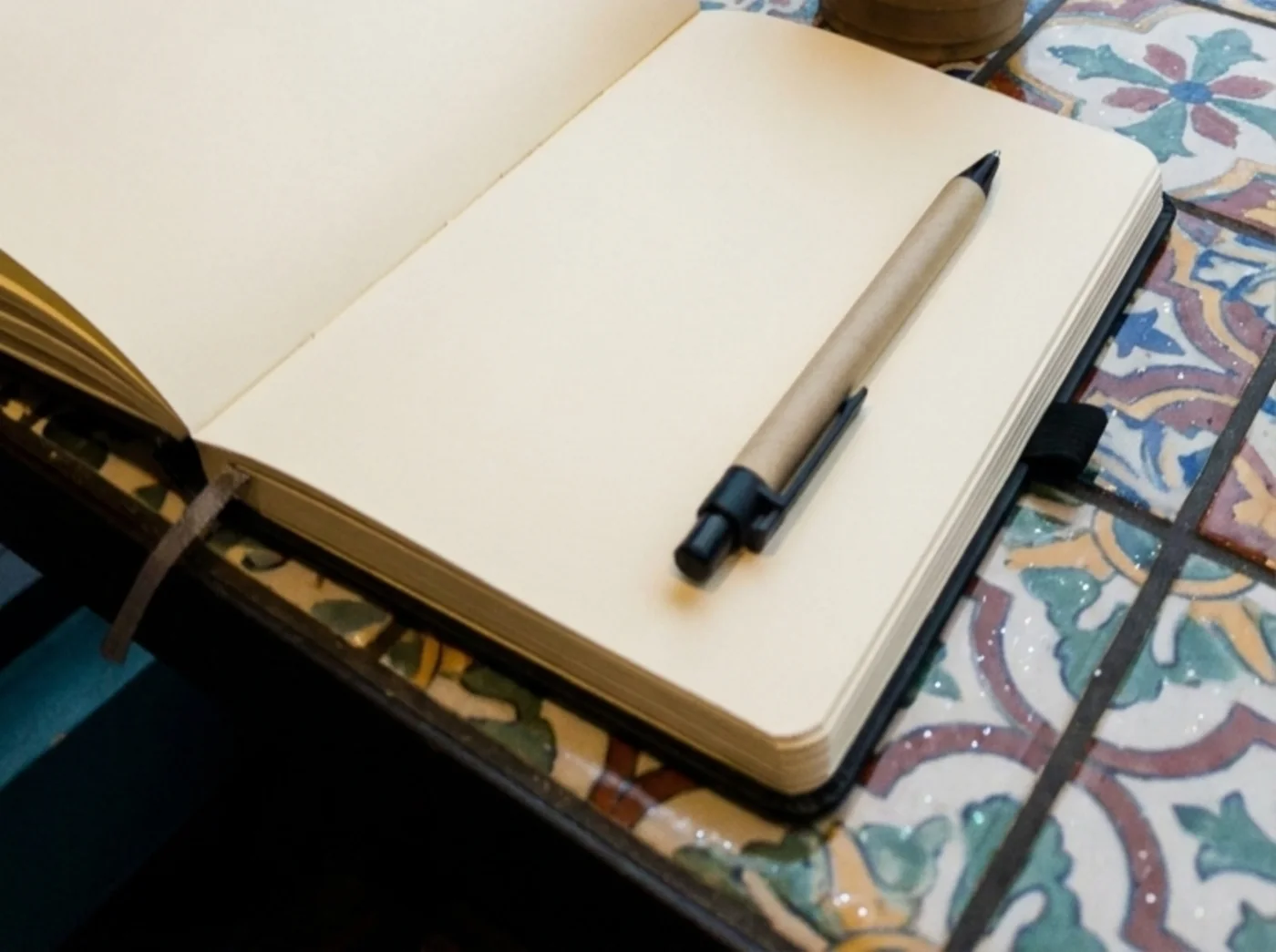 Open paper journal with a pen beside a rainy cafe window